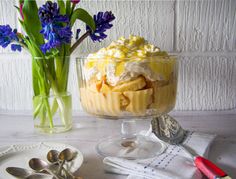 there is a dessert with flowers in the vase and spoons on the table next to it