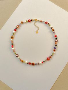 This necklace features cream, red, orange, mustard, matte transparent brown, and 24k gold plated seed beads. It also contains cream, green, purple, and orange crystal beads. As well as freshwater pearls, Amethyst, African Jade, sandstone, carnelian, agate, and copper spacer beads. Length: 16" inches Seed Bead Size: 11/0, 6/0, 2mm, 4mm, 6mm Adjustable: Each necklace has a 2" 18k gold filled lobster clasp extender Strung on: Non-Stretchy Beading Thread Please note: gemstones vary in color making each necklace a little unique! Orange Beads Necklace, Soft Autumn Jewelry, Beaded Flower Necklace, Necklace Colorful, Orange Crystals, Pretty Necklaces, Funky Jewelry, Fall Jewelry, Seed Bead Necklace