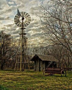 an old windmill sits in the middle of a grassy field next to a wooden bench