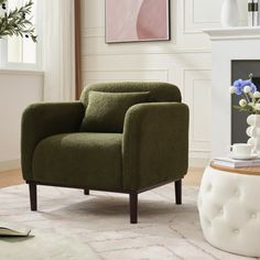 a living room with a green chair and white ottoman in front of a fire place