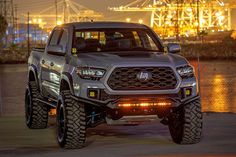 the front end of a silver truck with lights on it's bumpers and tires