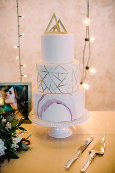 a white and gold wedding cake sitting on top of a table next to silverware