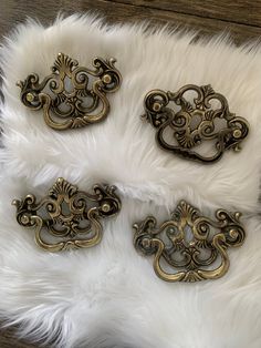 four antique brass drawer pulls on a white fur rug