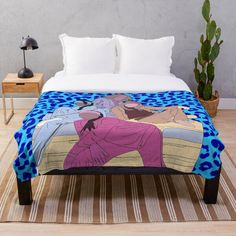 a bed with a blue and pink blanket on top of it next to a potted plant