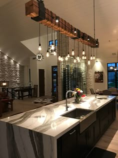 a kitchen with an island and lights hanging from it's ceiling over the sink