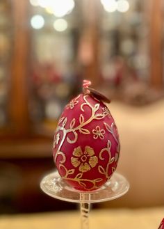 a red decorated egg sitting on top of a glass stand