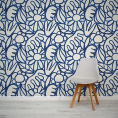 a white chair sitting in front of a wall with blue and white designs on it