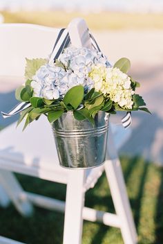 a bucket filled with flowers sitting on top of a white chair