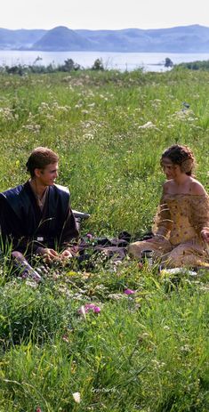 two people sitting in the grass talking to each other