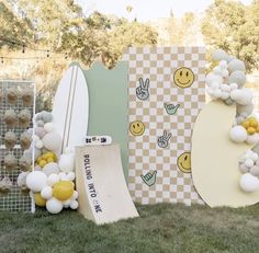 an assortment of balloons and surfboards are on display in the grass at a birthday party