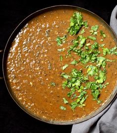 a metal pan filled with soup and garnished with cilantro, parsley