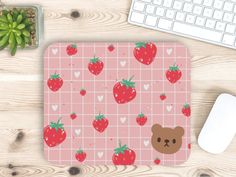 a mouse pad with strawberries and a teddy bear on it next to a keyboard