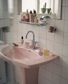 a pink sink in a white tiled bathroom