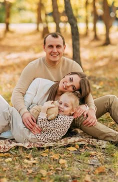 a man and woman sitting on the ground holding a baby