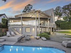 a house with a swimming pool in front of it at sunset or dusk, and steps leading up to the upper level