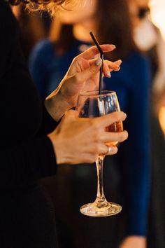 a woman holding a wine glass with a straw in it