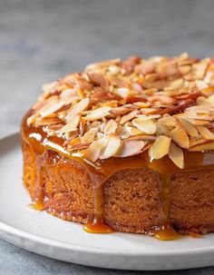 a cake on a white plate topped with almonds and caramel drizzle