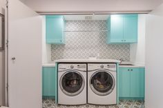 a washer and dryer in a small room with blue cabinets on the walls