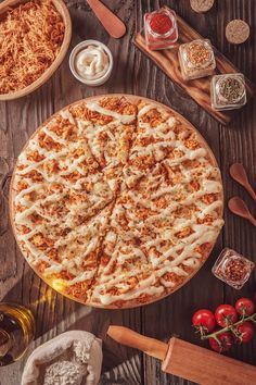 a pizza sitting on top of a wooden table next to other foods and utensils