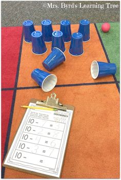 blue cups are sitting on the floor next to a clipboard with numbers and pencils