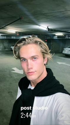 a man with blonde hair standing in a parking garage