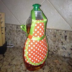 an orange and green bottle with polka dots on it sitting on a counter next to a cutting board