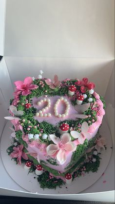 a heart shaped cake in a box with flowers and pearls on it's side