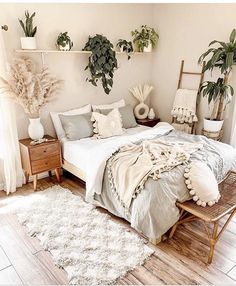 a bed sitting in a bedroom next to two potted plants