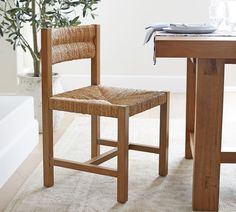 a wooden chair sitting next to a table with a vase on it's side