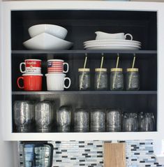 an open cabinet with cups and mugs on it