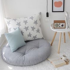 a room with white carpet and pillows on the floor next to a small round table