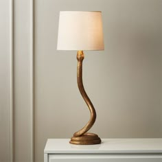 a lamp that is sitting on top of a white table next to a dresser with drawers