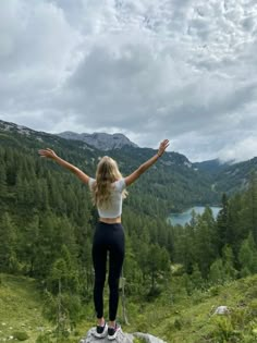 a woman standing on top of a rock with her arms wide open in the air