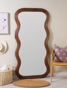 a mirror sitting on top of a wooden floor next to a chair and hat rack