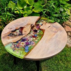 a wooden table sitting in the grass with flowers on it's side and a piece of wood that has been cut open