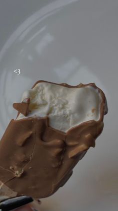 an ice cream sundae is being held by someone's hand with a cell phone