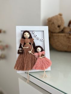 two dolls are in a frame on a table