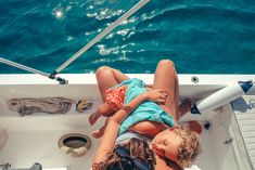 two people on a boat in the water with their arms around each other as they look at something