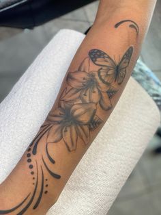 a woman's arm with flowers and butterflies tattooed on the side of her arm