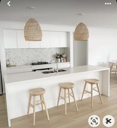 three stools are sitting at the bar in this white kitchen with wood flooring