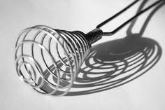 the shadow of a wire light bulb on a white surface with a long black cord