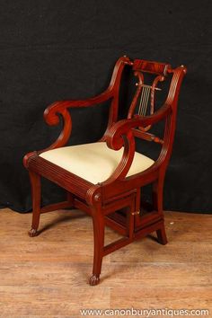 a wooden chair with a white cushion on it's seat and back rests against a black wall