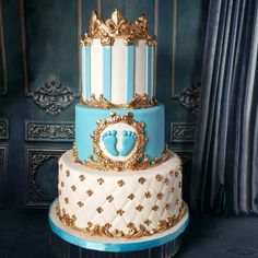 a three tiered blue and white cake with gold decorations