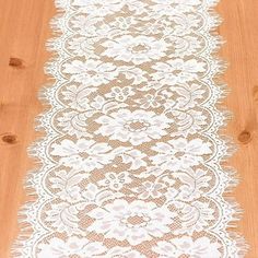 a white lace table runner sitting on top of a wooden floor