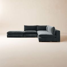 a large sectional couch sitting on top of a floor next to a chair and ottoman