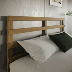 a bed with white sheets and pillows in a room next to a potted plant