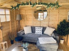 a living room with wood paneling and plants on the walls, couches, tables and mirrors