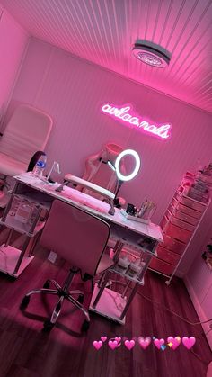 a pink room with a desk, chair and neon sign on the wall above it