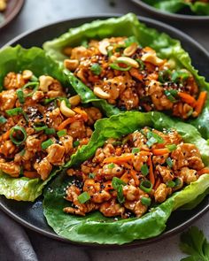 lettuce wraps filled with chicken and carrots on top of a black plate