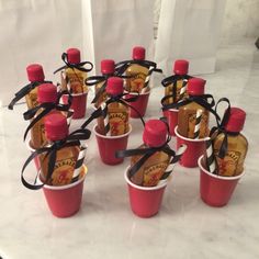 small red cups with black ribbon tied around them sitting on a white counter top, filled with ketchup bottles